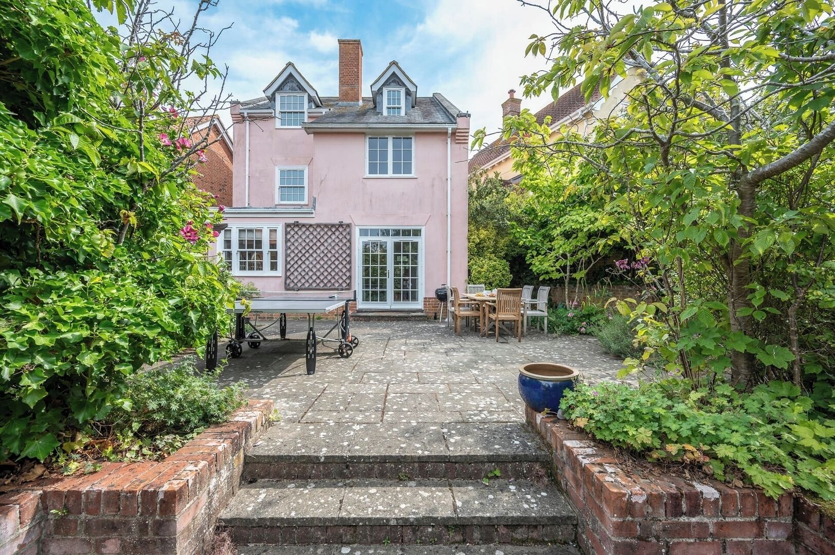 A pink house with a patio, a table, and chairs.