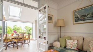 A room with a dining area, a sofa set, a lamp, and a framed picture on the wall.