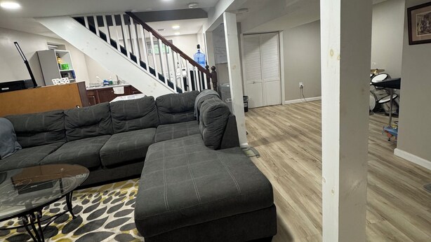 A spacious living area with a large sectional sofa, a glass coffee table, and a patterned rug. A staircase leads to an upper level. - Looking for a clean place to rest that won’t break the bank? Nestle offers that. (Woodbridge Township)