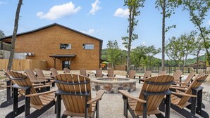 Een houten gebouw met een vuurkuil en Adirondack-stoelen op de voorgrond.