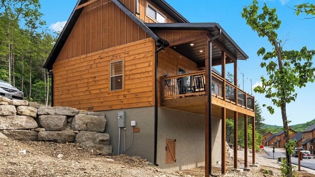 Een houten chalet met een balkon, stenen muur en uitzicht op het omliggende bos.