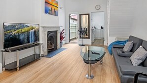 A modern living room with a fireplace, a TV, a glass coffee table, and a sofa.