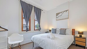 A bedroom with a bed, bedside tables, a chair, and a window with curtains.