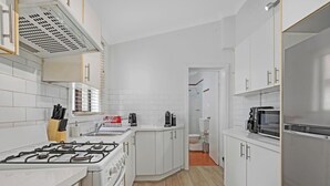 A modern kitchen with white cabinets, a gas stove, a microwave, and a refrigerator.