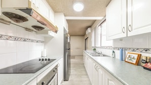 A kitchen with white cabinets, a stainless steel refrigerator, a stove, and a sink. - KozyGuru | Cabramatta | Spacious 3BR Townhouse (Cabramatta)