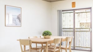 A dining area with a table and chairs, a potted plant, a framed picture on the wall, and a sliding glass door with a metal gate. - KozyGuru | Cabramatta | Spacious 3BR Townhouse (Cabramatta)