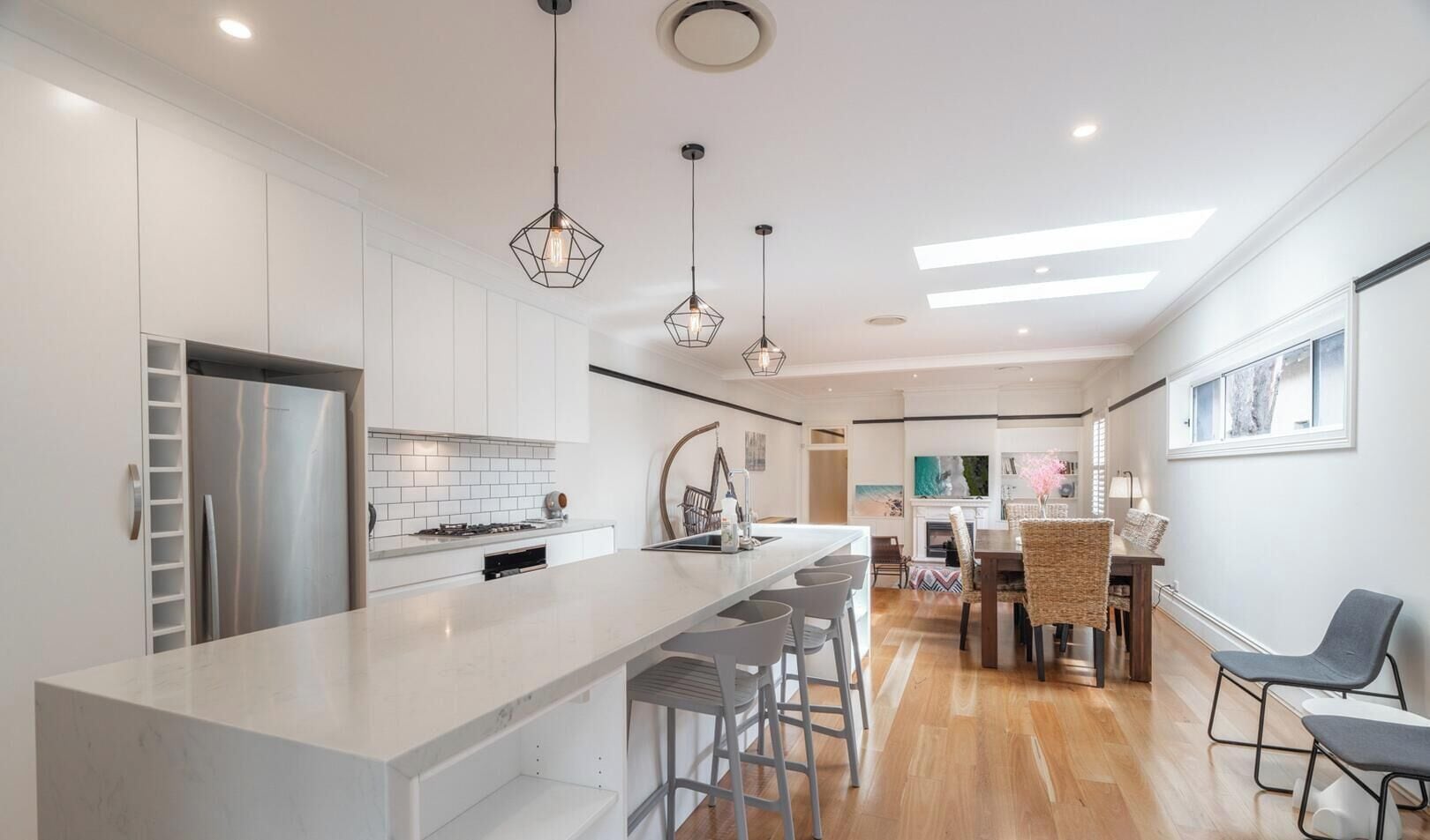 A modern kitchen with a central island, bar stools, and pendant lighting.