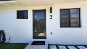 A modern building with a black door, a small window, and a number '3' on the wall. - Insta-Worthy Modern House in the Heart of Miami (Miami)
