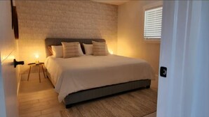 A bedroom with a bed, bedside table, and a window with blinds. - Insta-Worthy Modern House in the Heart of Miami (Miami)