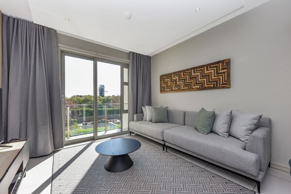 A modern living room with a grey sofa, a round coffee table, and a patterned rug.
