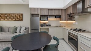 Eine moderne Küche mit Essbereich, inklusive einer zentralen Kochinsel, integrierter Geräte und zeitgemäßem Design.