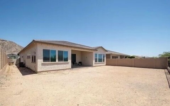 Una casa de un piso con techo plano, ventanas amplias y un patio cubierto.