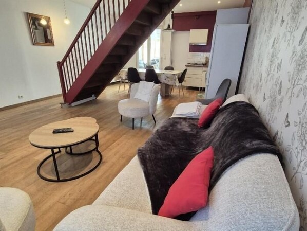 A living room with a sofa, a round coffee table, and a staircase. - Charming house between beach and town center (FOURAS)