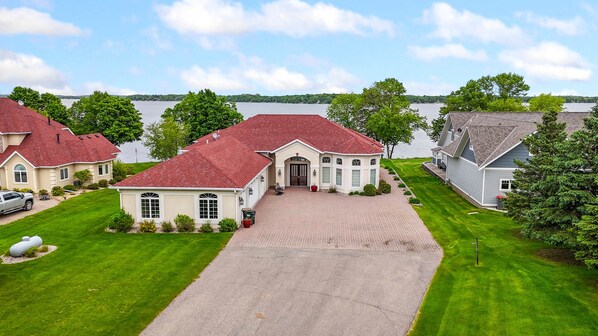 A large estate with a driveway leading to a main entrance, surrounded by well-maintained lawns and trees, overlooking a lake. - "The Luxe" on Lake Carlos (Carlos Township)