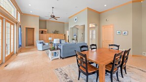 A spacious dining area with a wooden table and chairs, a sofa, and a ceiling fan. - "The Luxe" on Lake Carlos (Carlos Township)
