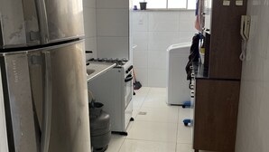 Uma cozinha com geladeira Bosch, fogão a gás e armário de madeira.
