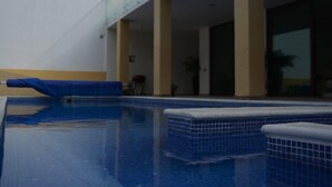A swimming pool with a glass balustrade, a covered area with a barbecue, and a view of a building with large windows. - hermosa residencia en ajijic con vista al lago (Ajijic)