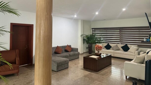 A modern living room with a large wooden column, a grey sofa, a white sofa, and a coffee table with a plant. - hermosa residencia en ajijic con vista al lago (Ajijic)