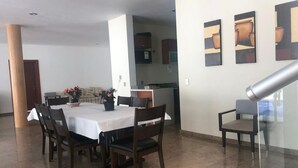 A dining area with a table set for four, surrounded by chairs, a kitchen in the background, and a staircase leading to an upper level. - hermosa residencia en ajijic con vista al lago (Ajijic)