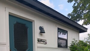 Uma casa com porta azul-turquesa, um letreiro de boas-vindas e uma pequena varanda com degraus.