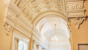 An ornate hallway with classical architecture, including detailed ceiling carvings and columns. - Washington by Interhome (Prague centre)