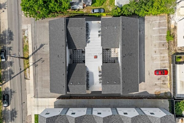 An aerial view of a parking lot with a central pedestrian walkway, surrounded by buildings.