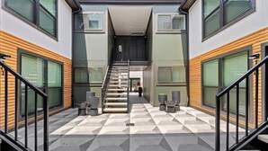Un edificio moderno con piso de diseño geométrico, una escalera central y ventanas amplias.