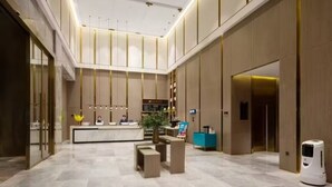 A spacious lobby with a reception desk, seating area, and a plant. - Echarm Plus International Hotel Hangzhou Binjiang XingGuang Avenue Pedestrian Street Branch (Hangzhou)