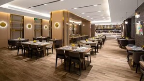 A modern restaurant with multiple dining areas, wooden flooring, and contemporary decor. - Echarm Plus International Hotel Hangzhou Binjiang XingGuang Avenue Pedestrian Street Branch (Hangzhou)