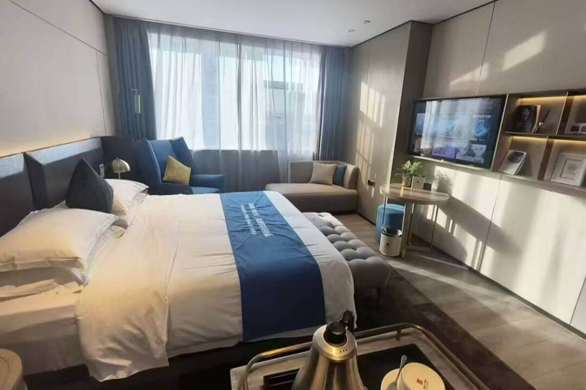 Una camera d'albergo con un letto grande, un divano, una TV e una macchina del caffè.