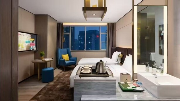 A modern hotel room with a bed, a seating area with a coffee table, a TV, and a bathroom with a large mirror and sink. - Echarm Plus International Hotel Hangzhou Binjiang XingGuang Avenue Pedestrian Street Branch (Hangzhou)