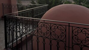 A balcony with ornate black metal railings and a large dome-shaped structure. - A haven of peace in Marrakech (Marrakech)
