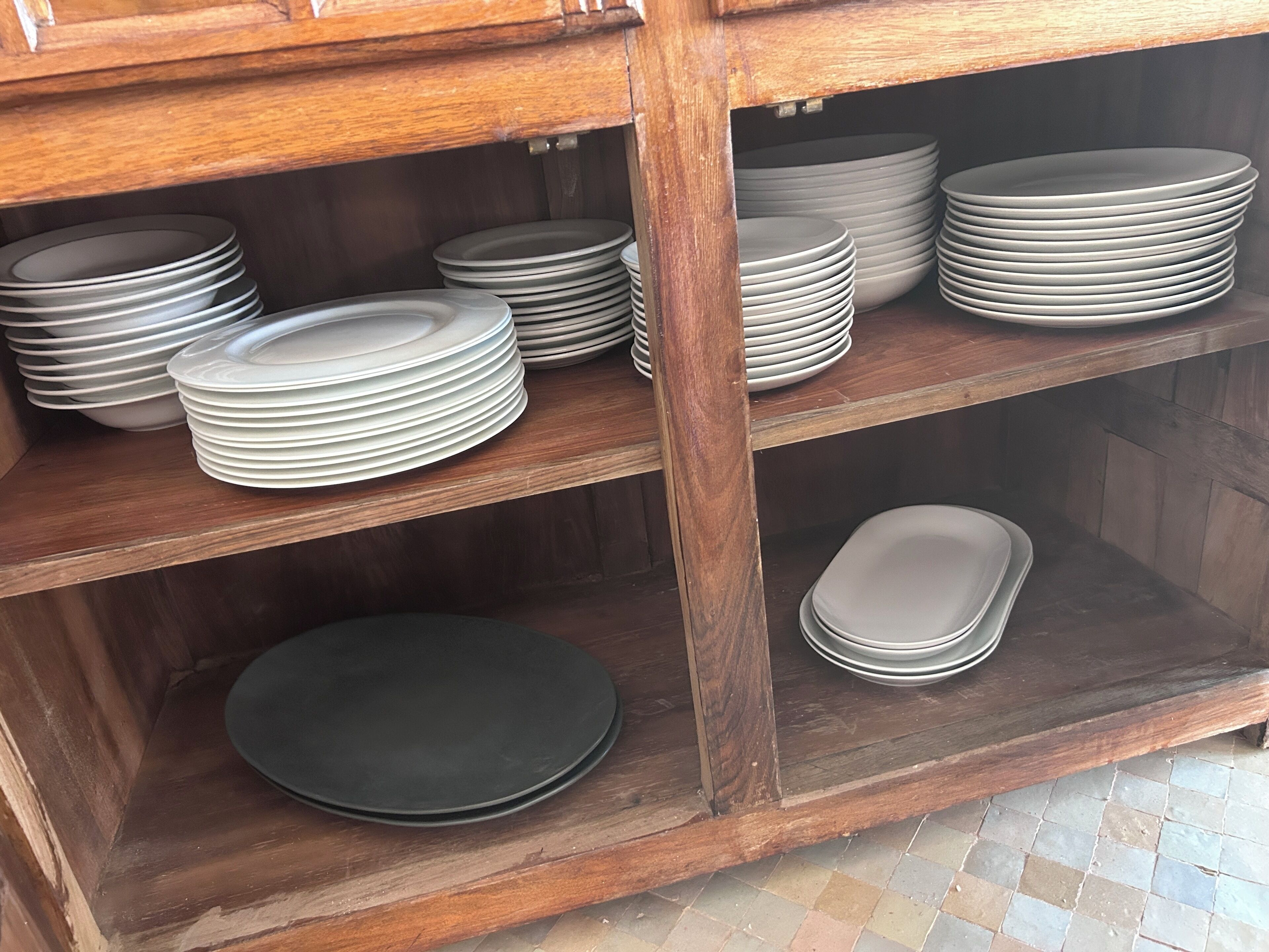 A wooden cabinet with multiple shelves holding stacks of plates.