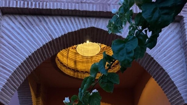An arched entrance with a wooden bench on either side, leading to a room with a patterned floor and a hanging light fixture. - A haven of peace in Marrakech (Marrakech)
