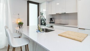 Eine moderne Küche mit weißen Schränken, einer Edelstahl-Spüle, einer Holz-Schneidebrett und einem kleinen Topfpflanze.