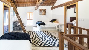 Une pièce comprenant un lit, une petite table, une chaise, une échelle en bois et un tableau accroché au mur.