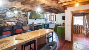Une cuisine rustique avec un mur en pierre, des poutres en bois et un îlot central de couleur verte.
