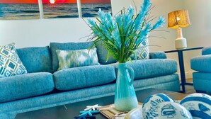 A living room with a blue sofa, a vase with blue flowers, and decorative items on a coffee table.