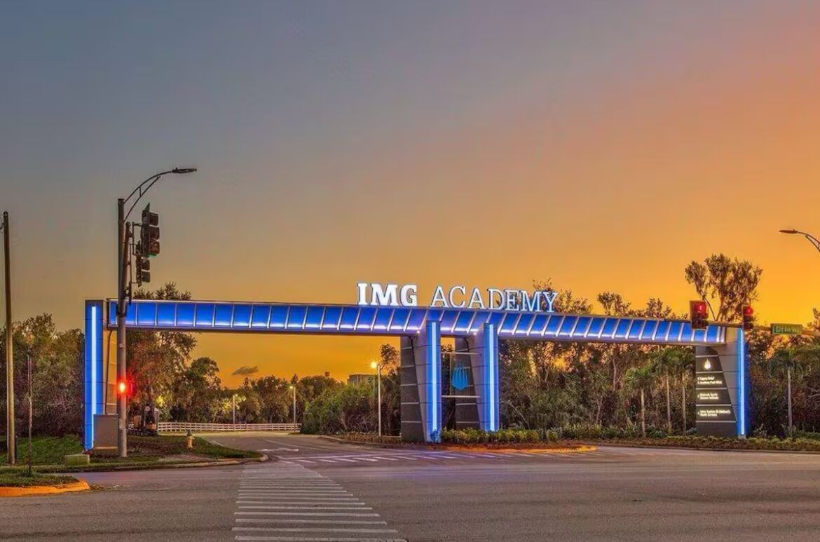 Der Eingang der IMG Academy mit einem blauen, beleuchteten Torbogen, Ampeln und blauem Himmel.