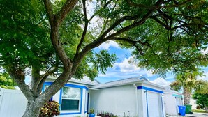 Una casa residencial con un árbol grande en el jardín delantero, un garaje y un césped bien cuidado.