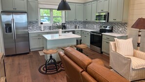 A modern kitchen with a central island, stainless steel appliances, and light-colored cabinetry. - Romantic Getaway at Honeymoon Cottage (Pisgah)