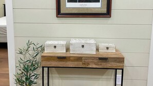 A framed photograph of a couple on a vintage car, a wooden console table with storage boxes, and a potted plant. - Romantic Getaway at Honeymoon Cottage (Pisgah)