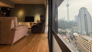 A modern living room with a sofa, a TV, and a view of a cityscape including a tower.