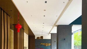 A modern indoor pool area with a clear view of the pool, a seating area with colorful chairs, and a wooden wall with vertical lines.