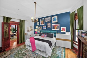 Un dormitorio con cama, mesita de noche y una pared decorada con marcos.