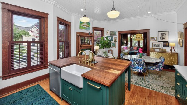A kitchen with wooden cabinets, a sink, and a dining area with a table and chairs. - Walk to 5 Points • 2 Living Areas • Game Room + Gym (Nashville)