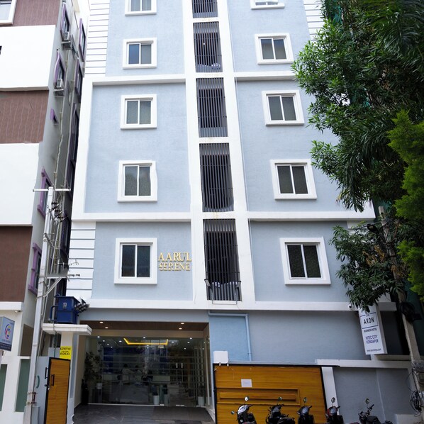 Un hotel de varios pisos con fachada moderna, que presenta una entrada central con puerta de vidrio y un cartel visible.