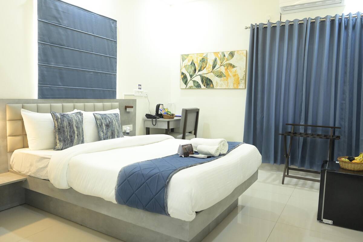 A modern hotel room with a large bed, a desk, and a chair.