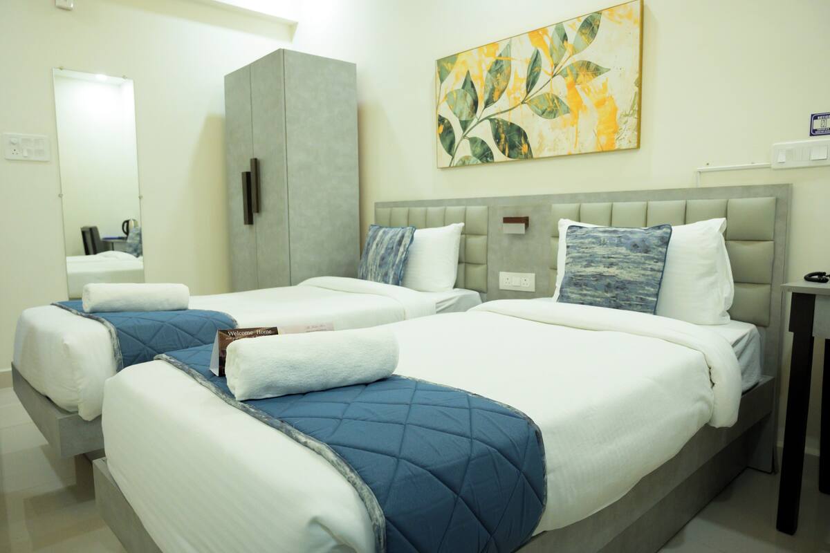 A hotel room with two beds, a wardrobe, a bedside table, and a wall-mounted artwork.