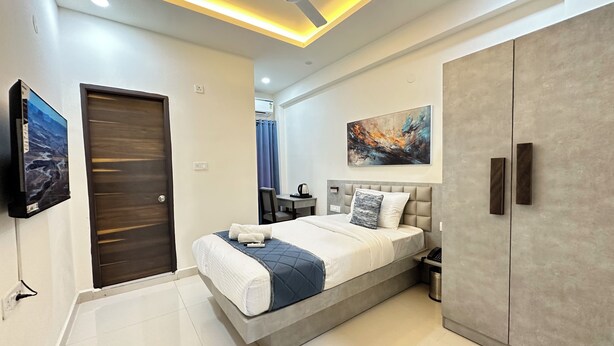 Une chambre à coucher moderne avec un lit, une armoire, un ventilateur de plafond, une télévision et un tableau au mur.